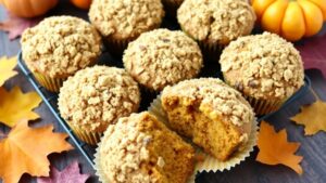 Freshly baked Apple Pumpkin Streusel Muffins on a wooden table with autumn decorations.